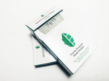 Load image into Gallery viewer, Product displayed resembles a white classic cigarette pack with a large seed/stem logo that is various shades of textured green.  The company logo is on the front flap and the text is in green label with font Manrope.  Pack is shown in plan view, front flap is partially open to reveal the silver foil that is labeled &#39;Pull&#39; There are two packs shown on angled on top of the other.  